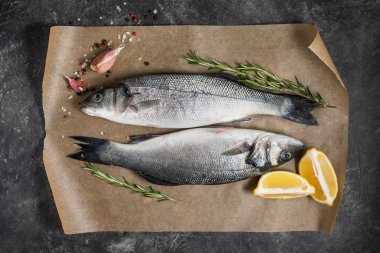 Taze balık levrek ve pişirme, limon ve biberiye için malzemeler. Koyu arka plan üst görünümü.