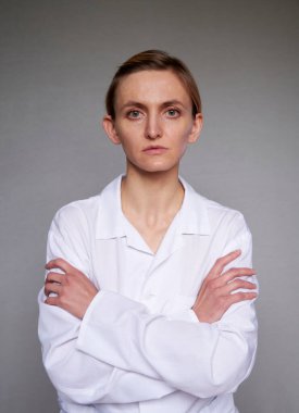 Gri arkaplan üzerinden kadın doktor ya da bilim adamı kapatın. Kollar göğüste çapraz