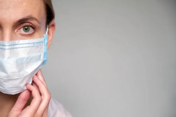 在灰色背景下戴着防护面罩的女医生或科学家的近照 她正在用手调整医疗面罩 — 图库照片