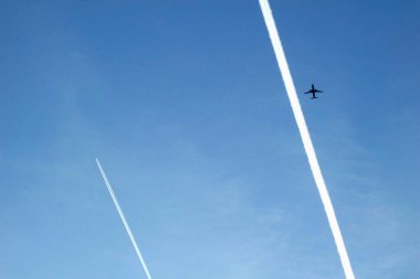 Uçak mavi gökyüzünde uçakla zıt düşüyor.