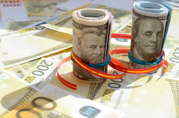 Rouleaux d'argent dans un ruban cadeau sur les factures de dollars et d'euros . — Photo