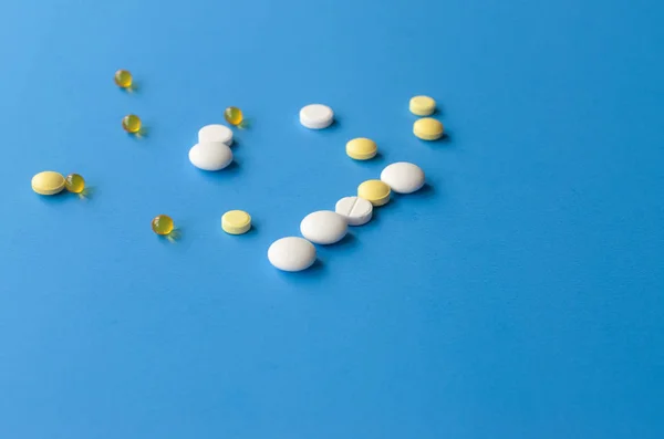 Chaotic scattered white and yellow pills on a blue background. — Stock Photo, Image