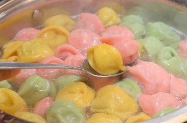 Bir tavada ve bir plaka üzerinde şenlikli bir menü için çok renkli Mantı piştiği.