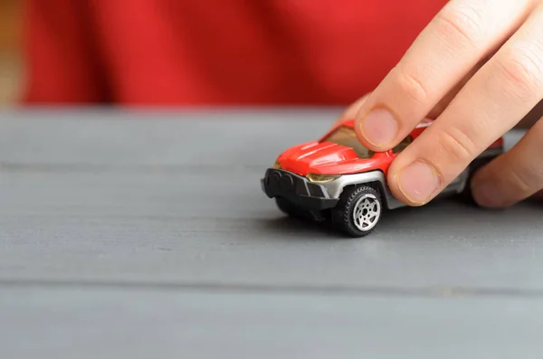 La mano del niño juega con una máquina de escribir roja sobre una superficie de madera de color oscuro . —  Fotos de Stock