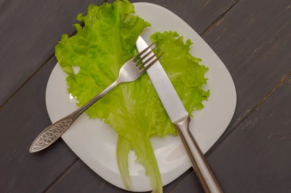 Salade laat op een witte plaat met mes en vork. Grijze houten achtergrond. Het begrip van gezond eten. — Stockfoto