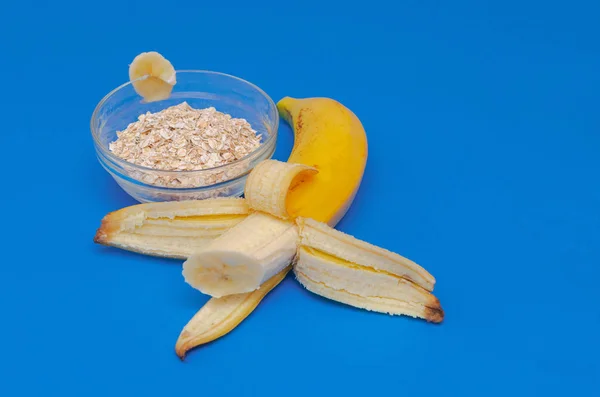 Banana madura e copo de aveia em um fundo azul. O conceito de alimentação saudável . — Fotografia de Stock