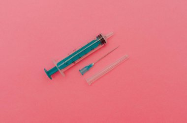 Pembe bir arka plan üzerinde yeşil piston ile şırınga. Sağlık kavramı.