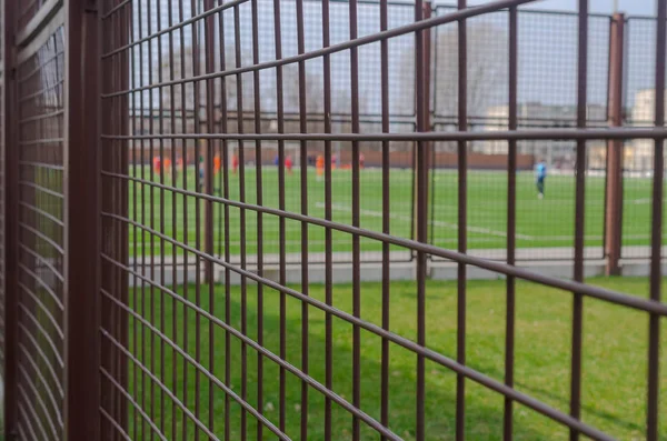 Football field through the iron bars of the fence. — Stock Photo, Image