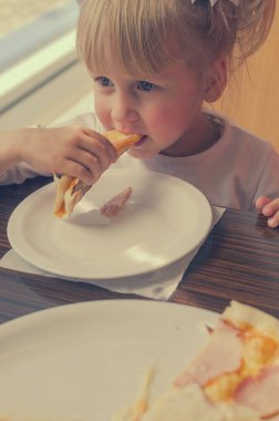 Bir kafede pizza yemek için bir iştah ile küçük kız.