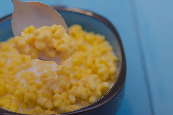 Maisbecher mit Frühstückszerealien auf blauem Holzhintergrund. — Stockfoto