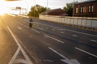 Ulaşım güvenliği kavramı. Gün batımı, köprüden iniş, motosiklet.