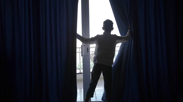 boy opens the curtains and goes to the balcony in the hotel