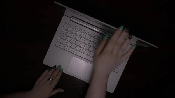 woman opens laptop, gray laptop on a wooden desk