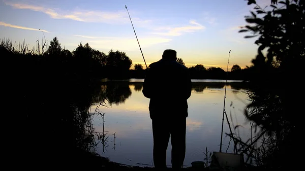 silhouette man fishing on the pond at sunset
