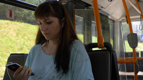 woman sitting on the bus and listening to music from phone