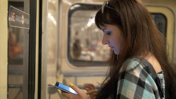 woman inside subway listening to music with phone