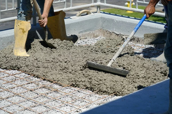 worker powering cement in the driveway construction site