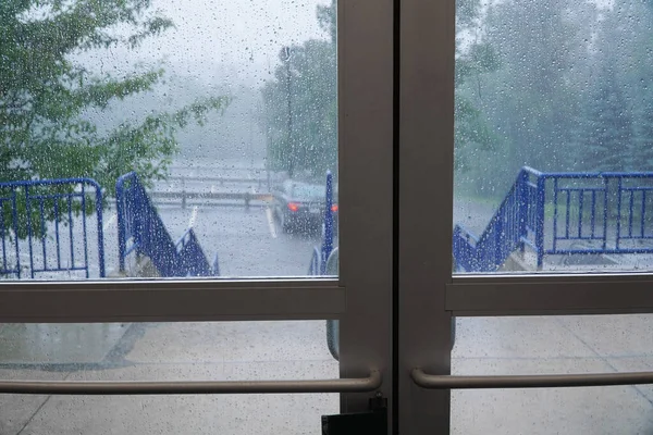 ガラスのドアの外の大雨の駐車場 ストック画像