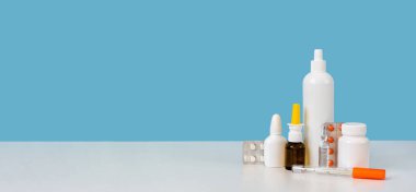 Fotokopi alanı olan pankart. İlaç malzemeleri: civa termometresi, beyaz plastik şişe, ampul, haplar ve burun spreyi. Parlak mavi arka plan. Ecza dolabı ya da eczane konsepti. Yakın çekim.