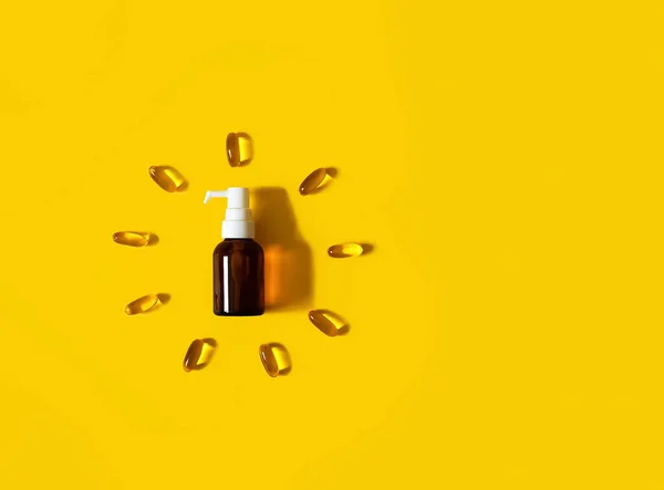 Kahverengi cam damlalar ve kapsüller parlak sarı arka planda güneş şeklinde duruyor. Sağlık sigortası konsepti. D vitamini, Omega 16, balık yağı. Kopyalama alanı