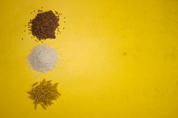 Sarı arka planda karabuğday, makarna ve pirinç..