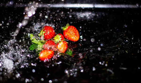 Siyah arka planda nane yapraklı çilek.