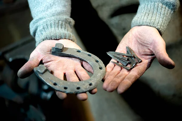 Close Een Vuile Smid Hand Houdt Een Paard Hoefijzer Nagels — Stockfoto