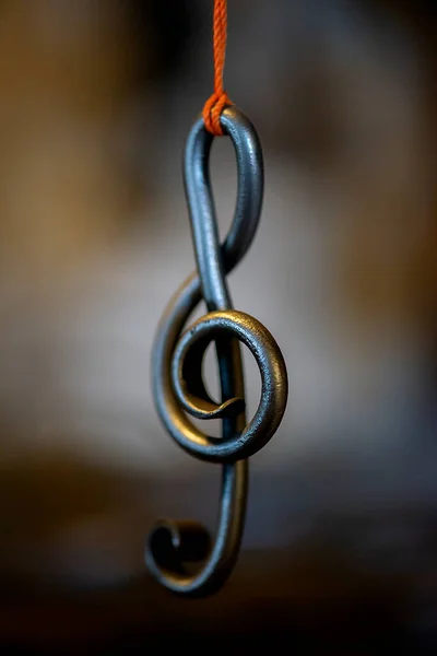 a metal sheet music key hangs in a rope in a blacksmith\'s workshop