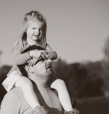 Mutlu baba oynuyor ve kızını omuzlarında taşıyor..