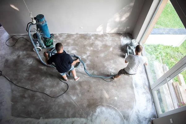 Epoksi döşemeyi kullanmadan önce beton zemini öğüten bir aile oturma odasında inşaat işçisi. Poliüretan ve epoksi döşeme. Beton öğütme..