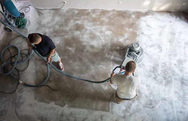 Epoksi döşemeyi kullanmadan önce beton zemini öğüten bir aile oturma odasında inşaat işçisi. Poliüretan ve epoksi döşeme. Beton öğütme..
