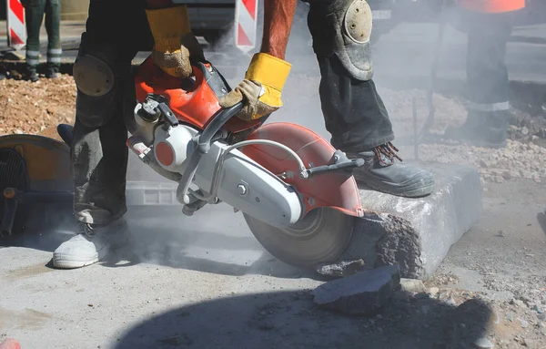 Yol inşaatında beton döşeyen makineli kesme makineli inşaat işçisi.