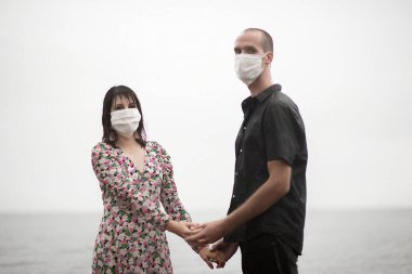Koruyucu yüz maskesi takan romantik bir çift beyaz, salgın ve duygu konseptine izole edilmiş.