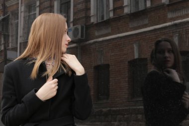 Siyah ceketli kız. Şehirdeki güzel, duygusal genç kız. Güzel kız elleriyle saçını tutuyor. Düşünen kadın. Çok düşünceli bir kadın. Bir insanın üzerinde şal ya da mendil. Kibirli görünüm