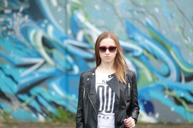 Grafiti duvarına karşı siyah deri ceketli güzel bir genç kız.