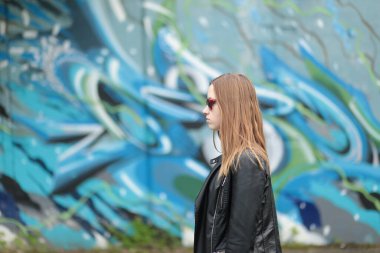 Grafiti duvarına karşı siyah deri ceketli güzel bir genç kız.
