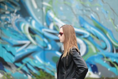Grafiti duvarına karşı siyah deri ceketli güzel bir genç kız.