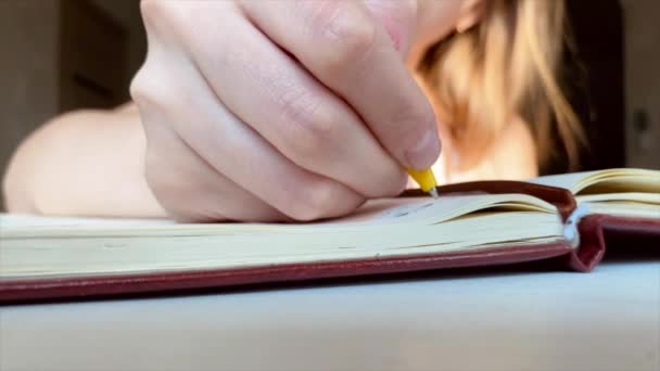 A menina loira está escrevendo em caderno com caneta amarela. Diário da mulher. Tomar notas — Vídeo de Stock