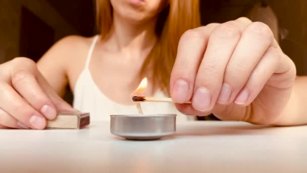 Dívka zapálí svíčku doma a dívá se, jak hoří — Stock video
