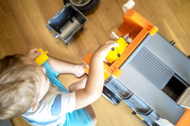 iki yıl yaşlı erkek çocuk oyuncaklarını güneşli oturma odasında arabalar ile oynuyor