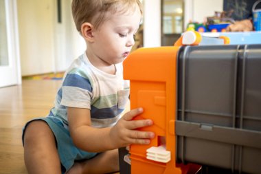 iki yıl yaşlı erkek çocuk oyuncaklarını güneşli oturma odasında arabalar ile oynuyor