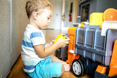 iki yıl yaşlı erkek çocuk oyuncaklarını güneşli oturma odasında arabalar ile oynuyor