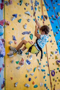 Genç çocuk bir yapay tırmanma üst için önde gelen bir ip asılı closeup duvar, kişisel gelişim ve kariyer büyüme veya kavramı destenizi