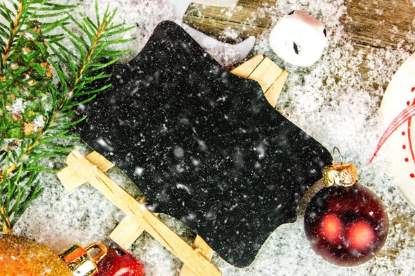 ブラック ボードでコピー スペースを木製の背景に降る雪とクリスマスの装飾 — ストック写真