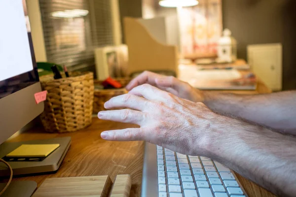 close-up of a man sitting at the desk and heavily praying with the typical wishing hands gesture in front of  the screen of desktop computer in the evening in the home office