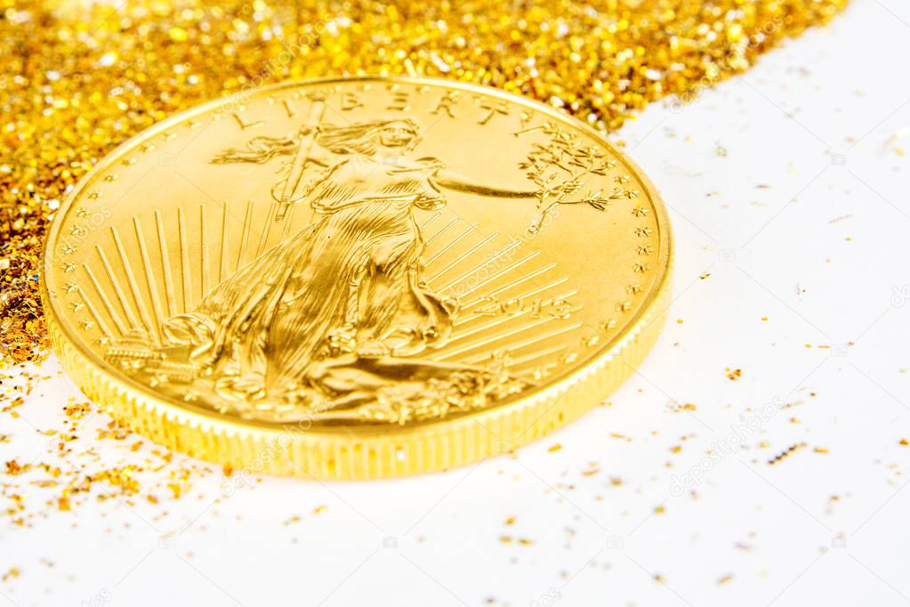 golden american eagle one ounce coin laying on glitering golden 