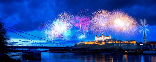 Widok nocy zamku Bratysława z powierzchni rzeki z dramatycznym widokiem i noworoczne fajerwerki — Zdjęcie stockowe