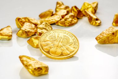 Altın Avusturyalı filarmoni sanatçısı bir ons altın külçe yığını üzerinde yatıyor, beyaz arka planda altın cevher bol miktarda kopya alanı ile izole edilmiş.