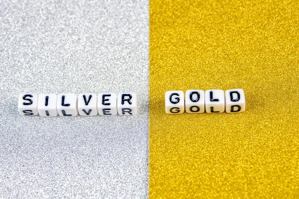 silver  and gold words formed by white dices with black letters  laying on silver and golden background, image split in two halves
