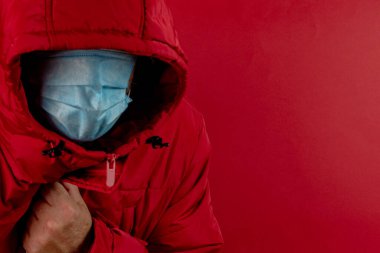 Kırmızı ceketli adam kırmızı zemin üzerinde Corona virüsüne karşı koruyucu bir maske kullanıyor, kırmızı alarm işareti ve hastalığa karşı dur işareti, COVID-19 SARS, SARS-CoV, virüs 2020 